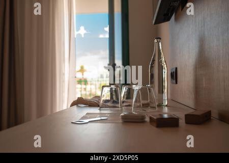 Begrüßungsgeschenke im Hotelzimmer mit drei Kristallgläsern, einer Kristallflasche Wasser mit Deckelöffner. Stockfoto