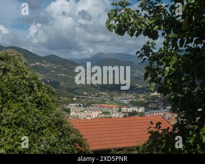 Blick aus der Vogelperspektive auf das Dorf Riva Trigoso von Punta Manara aus, Gebäude, Eisenbahn, Straßen und grüne Hügel am bewölkten Herbsttag. Sestri Levante, Ligurien, Italien Stockfoto