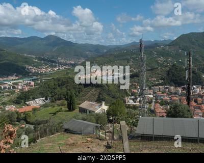 Blick aus der Vogelperspektive auf das Dorf Riva Trigoso von Punta Manara aus, Gebäude, Eisenbahn, Straßen und grüne Hügel am bewölkten Herbsttag. Sestri Levante, Ligurien, Italien Stockfoto