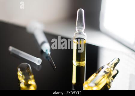 Nahaufnahme medizinischer Ampullen und Spritze auf reflektierender Oberfläche. Stockfoto