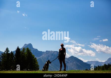 Eine Frau und ihr gemischter Schäferhund in Silhouette auf einer Wanderung im Kananaskis Country, einem beliebten Provinzpark in Alberta, Kanada Stockfoto