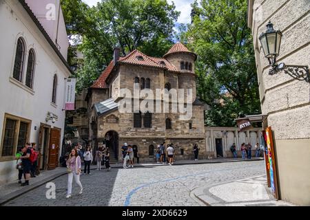 Prags jüdisches Viertel mit Touristen, die die historische Architektur des alten jüdischen Friedhofs und der Zeremonialhalle unter einem hellblauen Himmel erkunden. Stockfoto