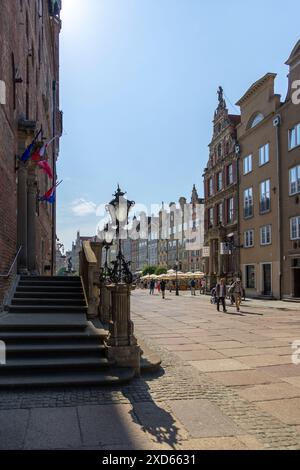 Ein ruhiger Moment in der Długa-Straße in Danzig, mit historischen Straßenlaternen, farbenfrohen Gebäuden und einem klaren blauen Himmel. Stockfoto