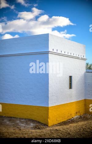 Ein wunderschön erhaltener Werkzeugschuppen mit weißen und gelben Wänden in der malerischen Provincia de Sevilla, España, unter hellem Himmel. Stockfoto