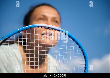 Eine Tennisspielerin, die sich intensiv auf ihr Spiel konzentriert, während sie einen Tennisschläger in der Nähe der Kamera hält. Das Bild erfasst einen Moment der Determina Stockfoto