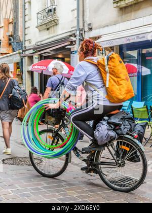 Frau auf dem Fahrrad mit einem Dutzend bunten Hula Hoop - Tours, Indre-et-Loire (37), Frankreich. Stockfoto