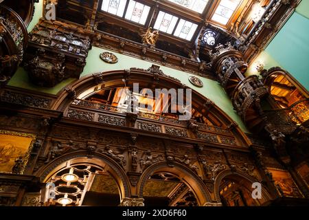 Sinaia, Rumänien - 26. August 2022: Wendeltreppe mit Holzschnitzereien und Holzdekoration im Ehrensaal im Schloss Peles. Das reichhaltige Interieur Stockfoto