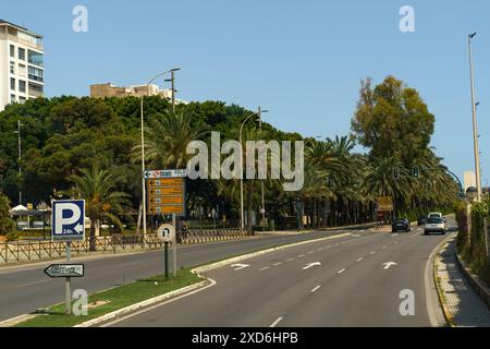 Almeria, Spanien - 25. Mai 2023: Eine von Palmen gesäumte Straße in Almeria, Spanien, mit einem Parkschild und Verkehrsschildern im Vordergrund. Stockfoto