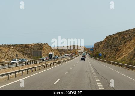 Almeria, Spanien - 25. Mai 2023: Blick auf eine Autobahn, die durch einen Bergpass in Spanien führt. Es gibt mehrere Autos und Lastwagen, die entlang der Roa fahren Stockfoto