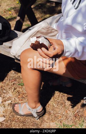 Eine Frau genießt ein Eis-Sandwich auf einer Picknickbank Stockfoto