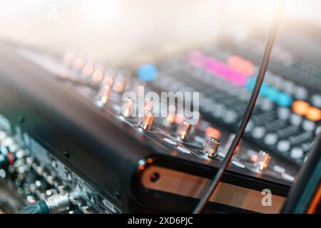 Audio-Mischpult im Musikstudio, Schwerpunkt auf Bedienknöpfen und Kabeln, mit verschwommenem Hintergrund für eine professionelle Atmosphäre. Stockfoto