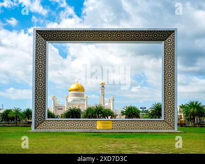 Brunei-Rahmen, Form eines Bilderrahmens auf grünem Gras im Taman Mahkota Jubli EMAS (TMJ) Park mit Blick auf den Masjid Omar Ali Saifuddien-Moschee Stockfoto