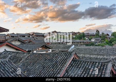 Traditionelle chinesische schwarze Ziegeldächer mit authentischen Häusern in der Altstadt von Lijiang, China. Fantastischer Blick auf den farbenfrohen Sonnenuntergang. Stockfoto