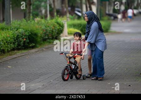 Kinder lernen im Wohnpark mit Mutter im Freien Fahrrad fahren Stockfoto