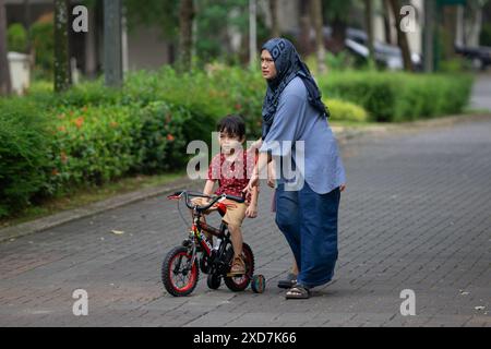 Kinder lernen im Wohnpark mit Mutter im Freien Fahrrad fahren Stockfoto