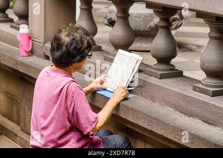 Taipeh, Taiwan - 22. April 2019: Ältere Chinesin liest ein Buch im Mengjia Longshan Tempel. Stockfoto
