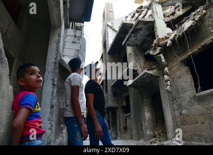 (240621) -- PEKING, 21. Juni 2024 (Xinhua) -- Mohammed Al-Aqad und seine Kinder schauen sich ihre vom Krieg beschädigte Wohnung im Lager Yarmouk in Damaskus, Syrien, 19. Juni 2024 an. Al-Aqad wurde in ein Vermächtnis der Vertreibung geboren. Seine Familie stammte ursprünglich aus Khan Younis in Gaza, aber wie viele Palästinenser im Jahr 1948 mussten sie ihre Heimat verlassen und suchten Zuflucht in Syrien. Die Familie Al-Aqad ließ sich im Lager Yarmouk südlich von Damaskus nieder und schaffte es, im Laufe der Jahre einen Anschein von Stabilität zu schaffen und besaß ein eigenes Wohngebäude in Yarmouk. Wie in den meisten Gebieten Syriens Stockfoto