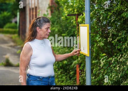 Ältere Frau an der Bushaltestelle Stockfoto