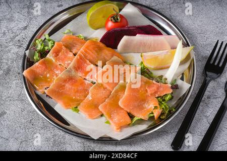 Räucherlachs mit Gemüse darunter auf einem Steintisch Stockfoto