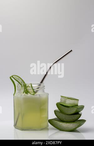 Aloe Vera Saft in einem Glas mit geschnittener und gestapelter Aloe Vera isoliert auf weißem Hintergrund. Stockfoto