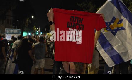 JERUSALEM – 20. JUNI: ein Demonstrant hält ein T-Shirt mit dem Text "du bist der Anführer, du bist schuldig" (in Bezug auf Premierminister Netanjahu) hoch, während regierungsfeindliche Demonstranten während einer Demonstration in der Nähe der Privatresidenz des Premierministers gegen die Regierung Netanjahus und der Forderung nach Neuwahlen am 20. Juni 2024 in Jerusalem Slogans singen. Israel Stockfoto