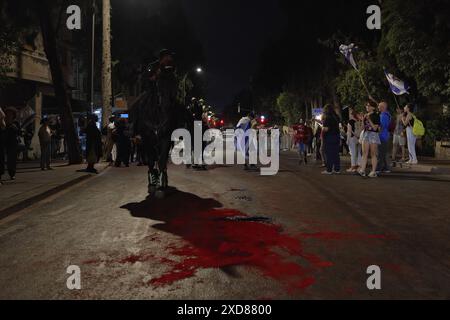 JERUSALEM - 20. JUNI: Die Polizei überquert rot gefärbtes Wasser, das die Anti-Regierung auf die Straße gegossen hat, um israelische Geiseln zu symbolisieren, die während einer Demonstration in der Nähe der Privatresidenz des Premierministers getötet wurden, gegen Netanjahus Regierung und rief zu neuen Wahlen am 20. Juni 2024 in Jerusalem auf. Israel Stockfoto