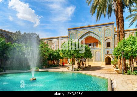 Fantastischer Brunnen mitten im traditionellen persischen Innenhof mit grünem Garten in Madrese e-Khan in Shiraz, Iran. Stockfoto