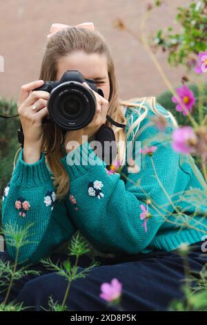 Frau in einem grünen Pullover, die ein Foto mit einer Kamera in einer Garde macht Stockfoto