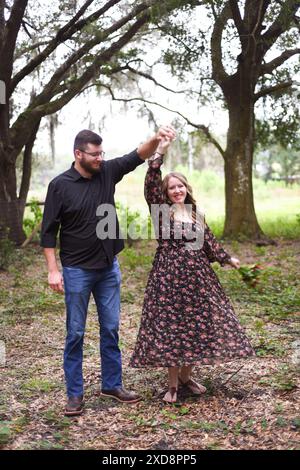Schwangere Paare tanzen im Wald, lächelnde Frau, die sich reindreht Stockfoto