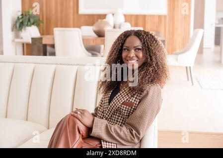 Frau, die sich zu Hause auf einer Couch entspannt und lächelt Stockfoto
