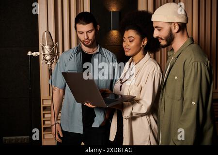 Drei Personen arbeiten in einem Aufnahmestudio zusammen und betrachten Musik auf einem Laptop-Bildschirm. Stockfoto