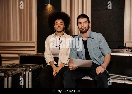 Ein Mann und eine Frau arbeiten in einem Tonstudio zusammen, umgeben von Musikinstrumenten und Geräten. Stockfoto