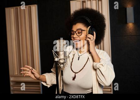 Eine junge Frau singt leidenschaftlich in ein Mikrofon, umgeben von Musikgeräten in einem Aufnahmestudio während einer Bandprobe. Stockfoto