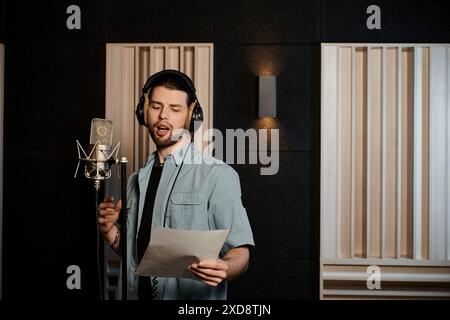 Ein Mann singt leidenschaftlich in einem Aufnahmestudio während einer Musikband-Probe. Stockfoto