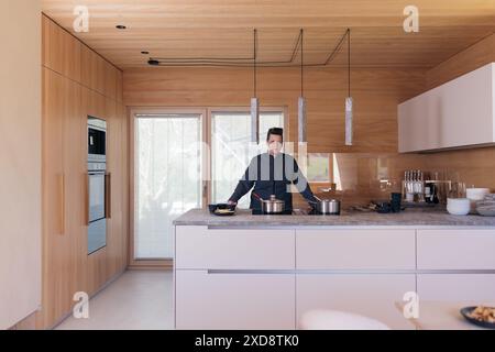 Küchenchef in einer modernen Holzküche mit minimalistischem Design Stockfoto