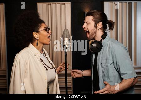 Ein Mann und eine Frau singen leidenschaftlich in ein Mikrofon in einem Aufnahmestudio während einer Musikbandprobe. Stockfoto