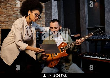 Ein Mann und eine Frau spielen leidenschaftlich Gitarre in einem Aufnahmestudio während einer Musikbandprobe. Stockfoto