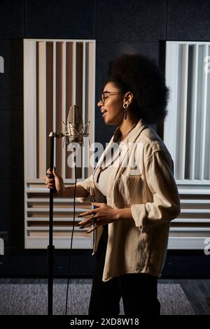 Eine talentierte Frau singt leidenschaftlich in das Mikrofon während der Musikbandprobe im Aufnahmestudio. Stockfoto