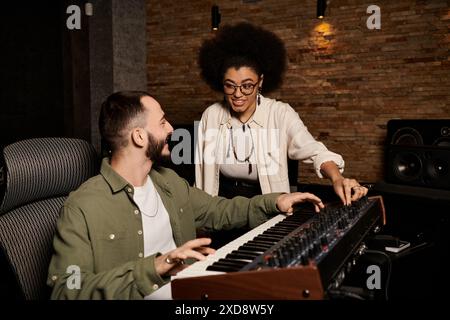 Ein Mann und eine Frau arbeiten in einem Tonstudio zusammen, in dem sie Musik für ihre Bandprobe kreieren. Stockfoto