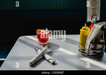 Roter Cocktail auf einem Esstisch mit Gewürzen und Servietten. Stockfoto
