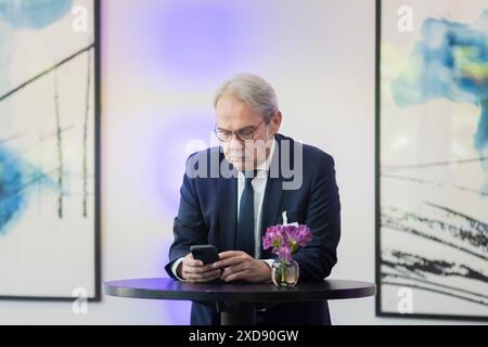 Potsdam, Deutschland. Juni 2024. Georg Maier (SPD), Innenminister Thüringens, schaut sich sein Smartphone während der Arbeitssitzung am letzten Tag der Frühjahrstagung der Innenminister und Innensenatoren im Hotel Dorint an. Quelle: Christoph Soeder/dpa/Alamy Live News Stockfoto