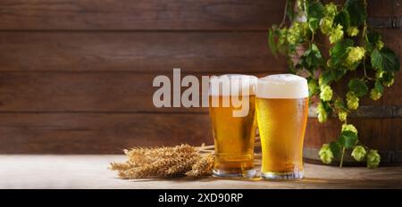 Gläser Bier, Weizenohren und Hopfen auf einem hölzernen Hintergrund Stockfoto