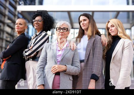 Vier multirassische Geschäftsfrauen posieren lächelnd vor der Kamera. Stockfoto