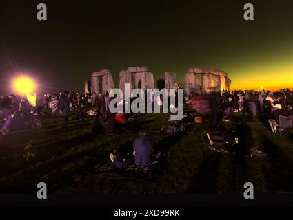 Salisbury, England, Großbritannien. Juni 2024. Eine Menschenmenge versammelt sich um die Basis der Steine und die Sonne untergeht während der Sommersonnenfeier in Stonehenge. Stonehenge wurde vor etwa 4000 Jahren von den frühen Briten gebaut, um sich an den Sonnenzeiten an der Sonne auszurichten. Die Sommersonnenwende markiert das Ende des Frühlings und den Beginn des Sommers und ist der längste Tag und die kürzeste Nacht in der nördlichen Hemisphäre. Die Veranstaltung wird von Tausenden von Heiden weltweit mit Gesang und Tanz gefeiert. (Kreditbild: © Martin Pope/ZUMA Press Wire) NUR REDAKTIONELLE VERWENDUNG! Nicht für kommerzielle ZWECKE! Stockfoto