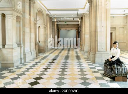 Frau sitzt in einem Museumsflur mit kariertem Boden und Säulen, Edinburgh, Schottland Stockfoto