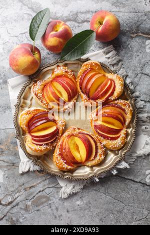 Gebackener Peach Blätterteigkuchen mit frischem Obst und Marmelade in Nahaufnahme auf einem Teller auf dem Tisch. Vertikale Draufsicht von oben Stockfoto