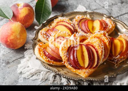 Köstliches Dessert Pfirsich Blätterherzkuchen mit frischem Obst und Marmelade in Nahaufnahme auf einem Teller auf dem Tisch. Horizontal Stockfoto