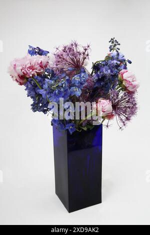 Blumenstrauß mit Pfingstrosen in einer rechteckigen Vase aus blauem Glas Stockfoto
