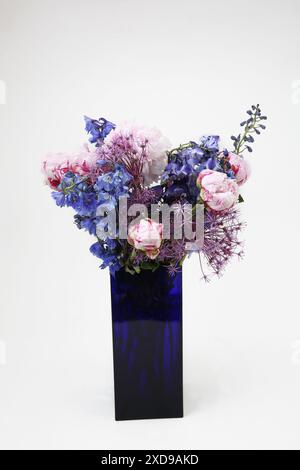 Blumenstrauß mit Pfingstrosen in einer rechteckigen Vase aus blauem Glas Stockfoto