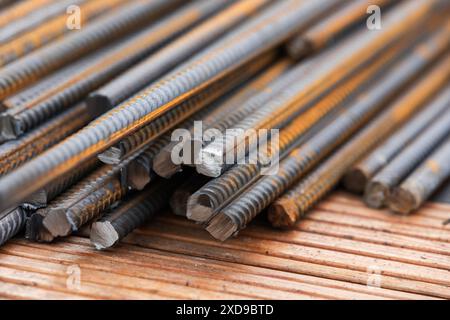 Baueisenstäbe mit Rostflecken lagen auf einem hölzernen Schreibtisch, abstraktes industrielles Hintergrundfoto Stockfoto